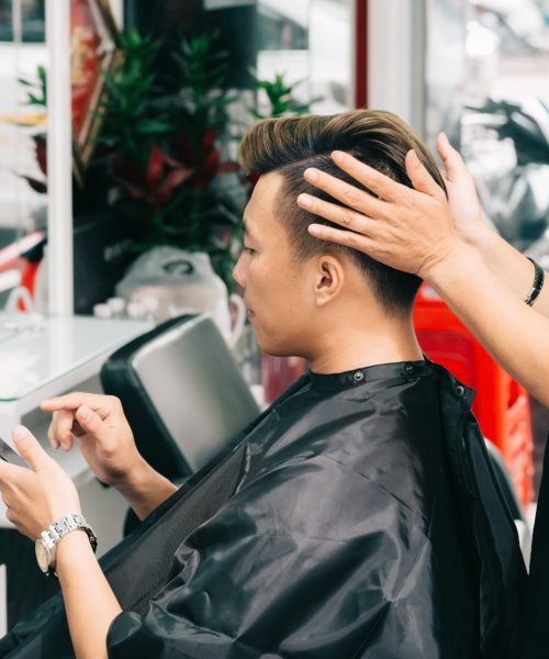 Barber making final touches on haircut of male client